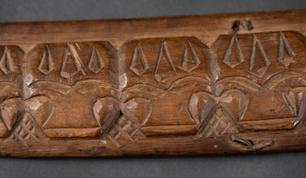 Very fine old sword from the Paiwan tribe, with a scabbard carved with multiple human faces. One side is inlaid with three faience circles.