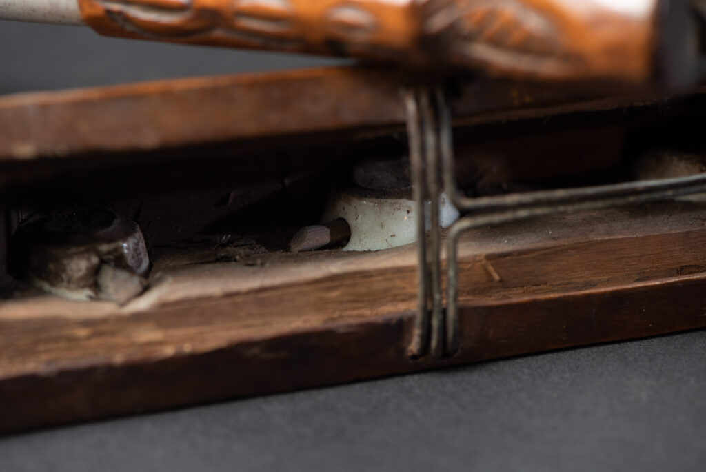 Very fine old sword from the Paiwan tribe, with a scabbard carved with multiple human faces. One side is inlaid with three faience circles.