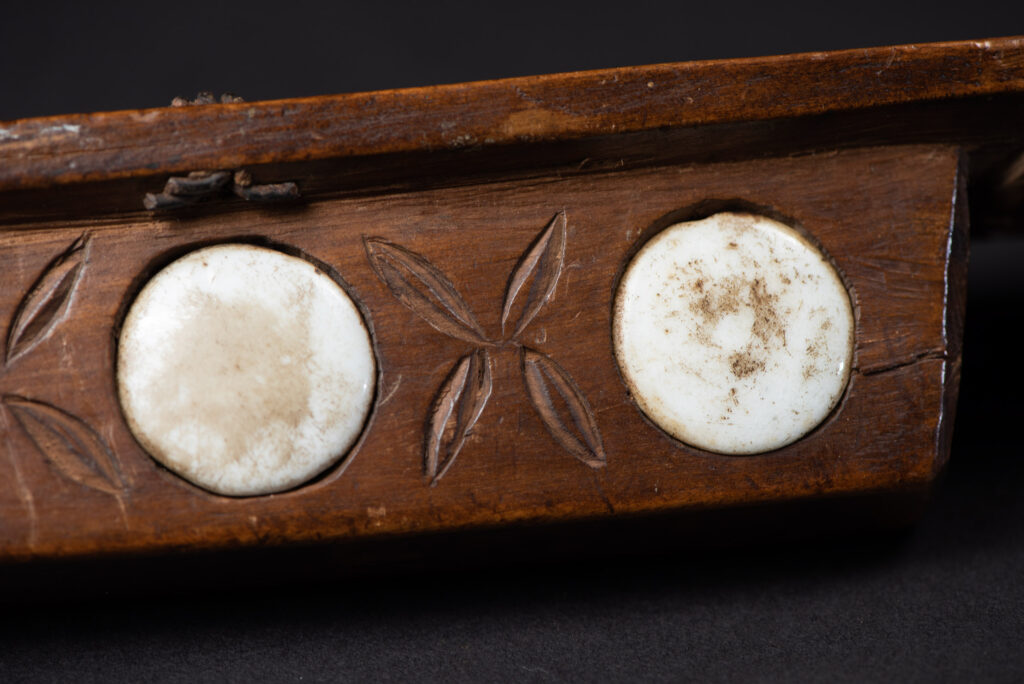 Very fine old sword from the Paiwan tribe, with a scabbard carved with multiple human faces. One side is inlaid with three faience circles.