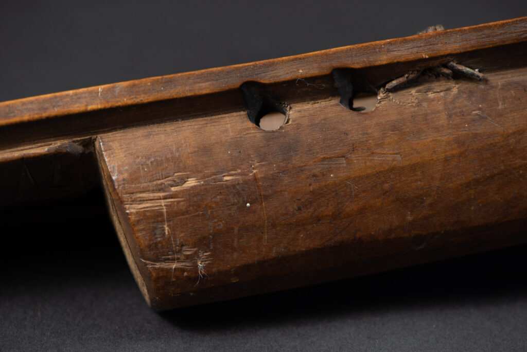 Very fine old sword from the Paiwan tribe, with a scabbard carved with multiple human faces. One side is inlaid with three faience circles.