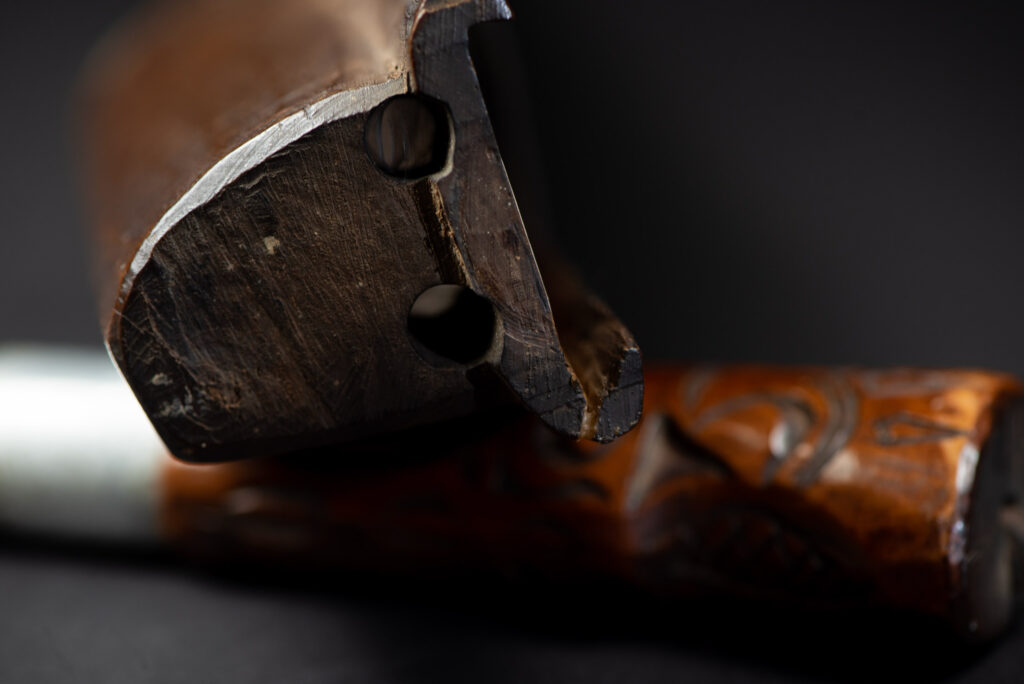 Very fine old sword from the Paiwan tribe, with a scabbard carved with multiple human faces. One side is inlaid with three faience circles.