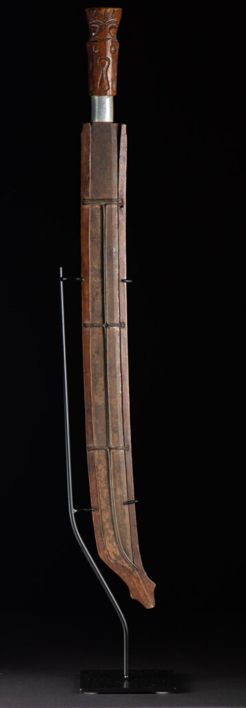 Very fine old sword from the Paiwan tribe, with a scabbard carved with multiple human faces. One side is inlaid with three faience circles.