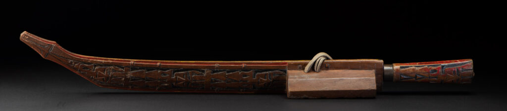 Paiwan tribe sword with a sheath carved with several standing figure and painted in red.