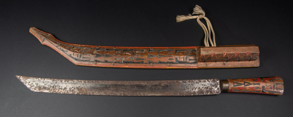 Paiwan tribe sword with a sheath carved with several standing figure and painted in red.