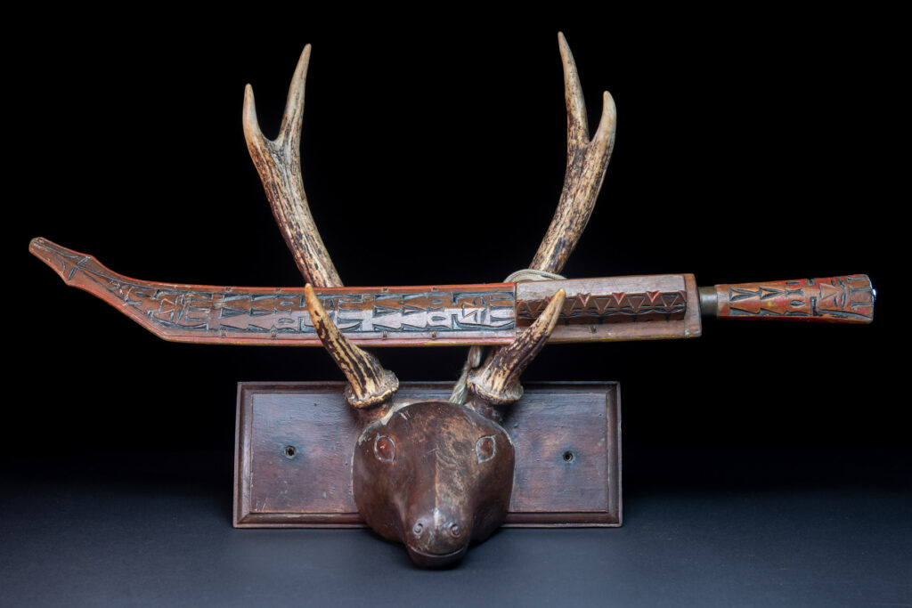 Paiwan tribe sword with a sheath carved with several standing figure and painted in red.