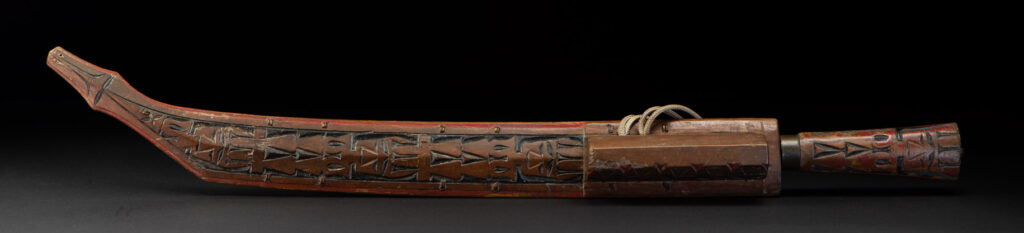 Paiwan tribe sword with a sheath carved with several standing figure and painted in red.