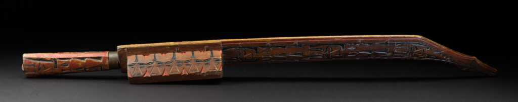 Paiwan tribe sword with a sheath carved with several standing figure and painted in red.