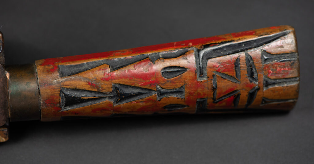 Paiwan tribe sword with a sheath carved with several standing figure and painted in red.