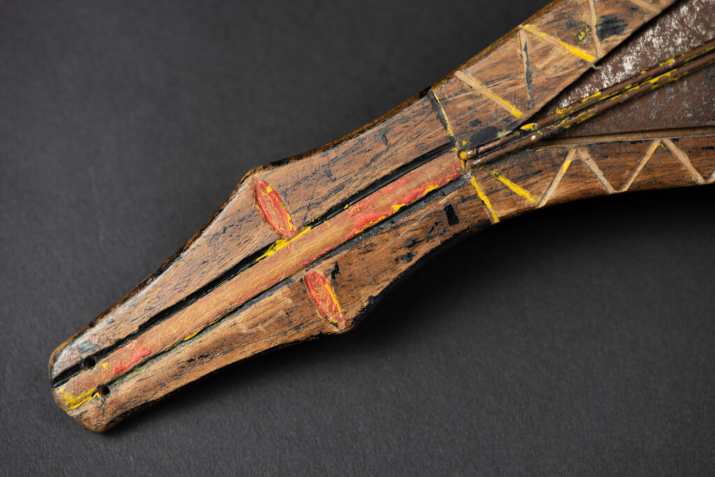 Paiwan tribe sword with a sheath carved with several standing figure and painted in red.