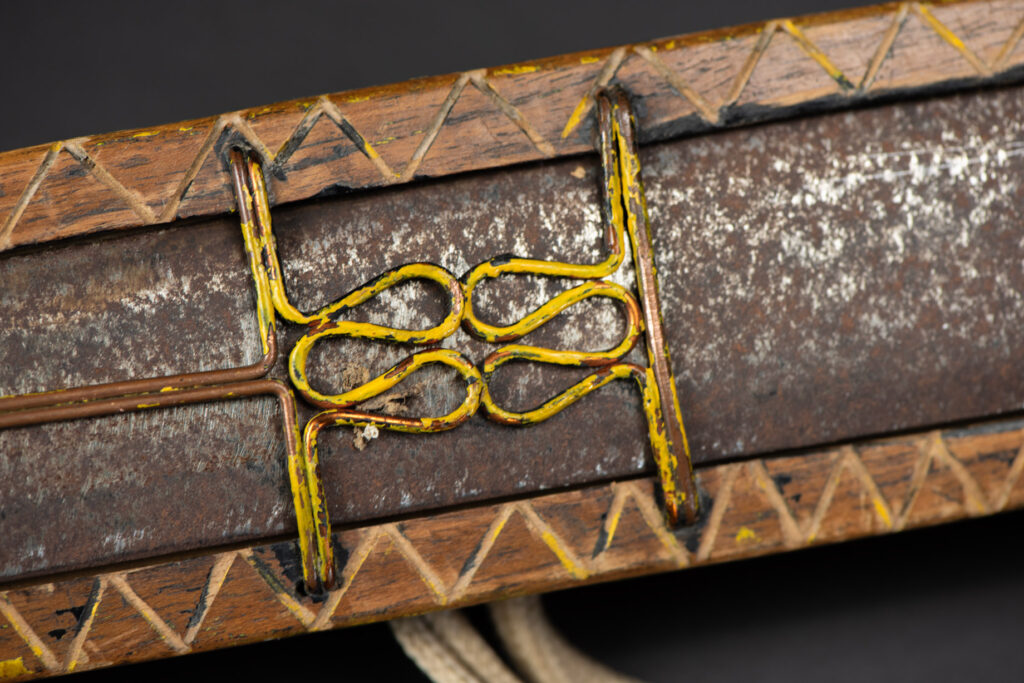 Paiwan tribe sword with a sheath carved with several standing figure and painted in red.