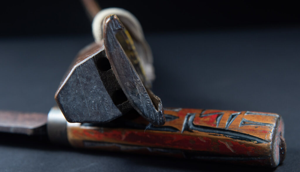 Paiwan tribe sword with a sheath carved with several standing figure and painted in red.