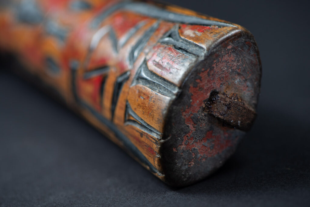 Paiwan tribe sword with a sheath carved with several standing figure and painted in red.