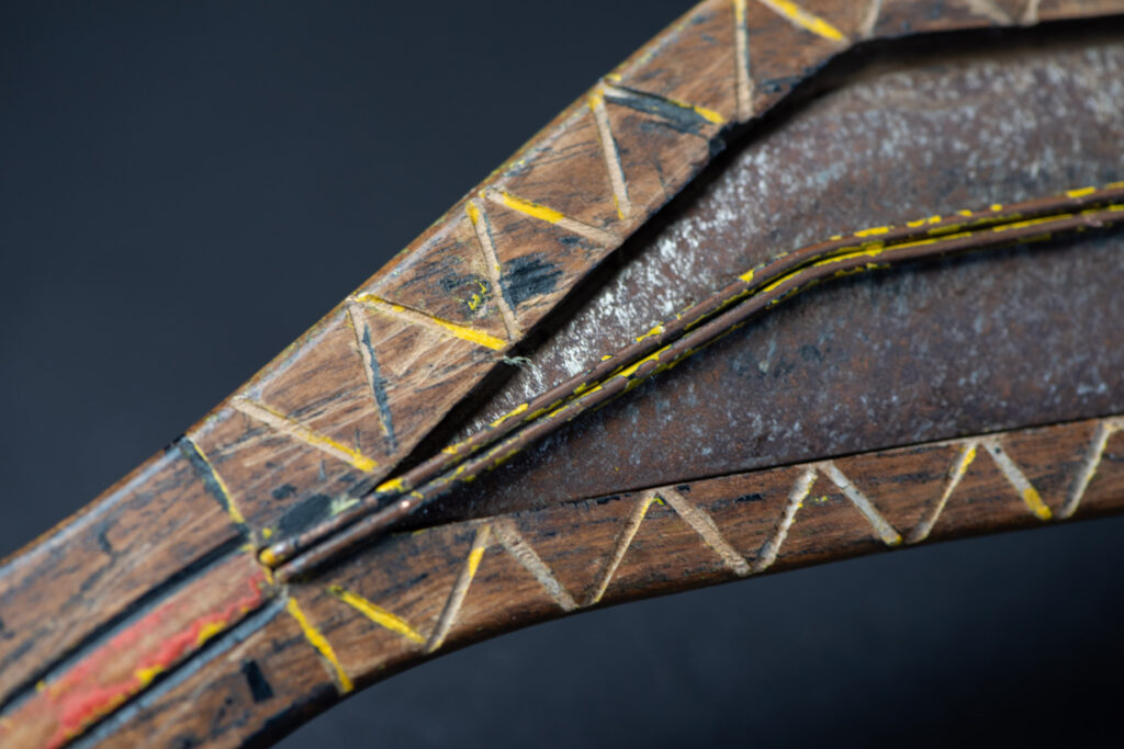 Paiwan tribe sword with a sheath carved with several standing figure and painted in red.