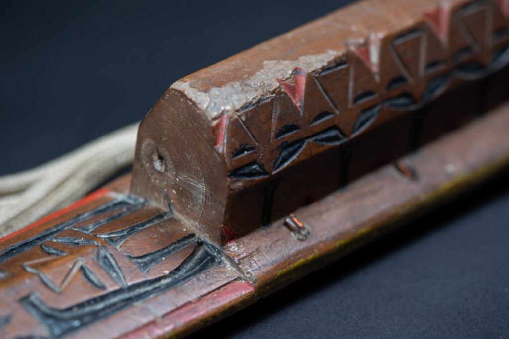 Paiwan tribe sword with a sheath carved with several standing figure and painted in red.