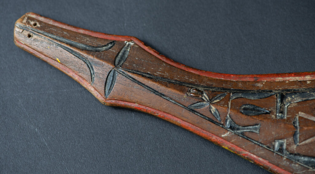 Paiwan tribe sword with a sheath carved with several standing figure and painted in red.