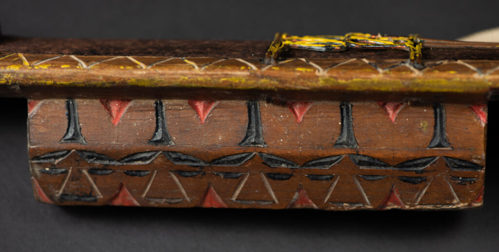 Paiwan tribe sword with a sheath carved with several standing figure and painted in red.