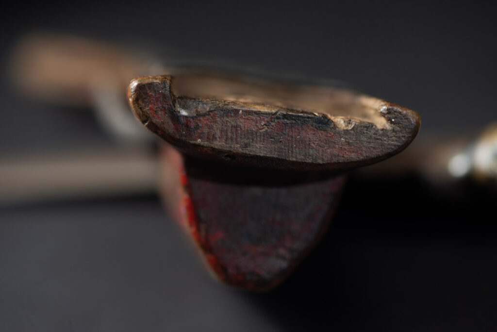 Paiwan tribe hunting knife with a sheath carved with a standing figure and painted in red. The blade and handle are forged as one piece, with the grip wrapped in rattan for protection.