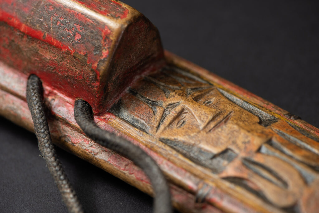 Paiwan tribe hunting knife with a sheath carved with a standing figure and painted in red. The blade and handle are forged as one piece, with the grip wrapped in rattan for protection.