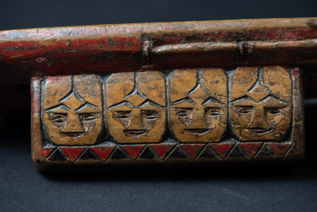 Paiwan tribe hunting knife with a sheath carved with a standing figure and painted in red. The blade and handle are forged as one piece, with the grip wrapped in rattan for protection.