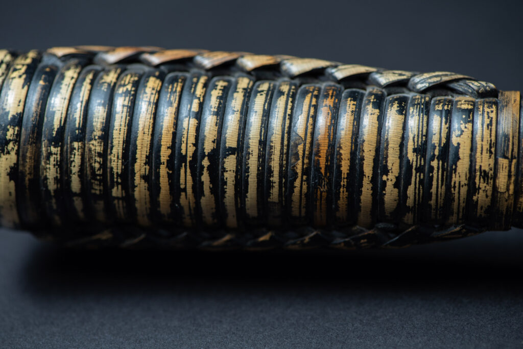 Paiwan tribe hunting knife with a sheath carved with a standing figure and painted in red. The blade and handle are forged as one piece, with the grip wrapped in rattan for protection.