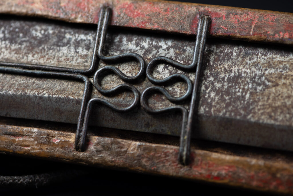 Paiwan tribe hunting knife with a sheath carved with a standing figure and painted in red. The blade and handle are forged as one piece, with the grip wrapped in rattan for protection.