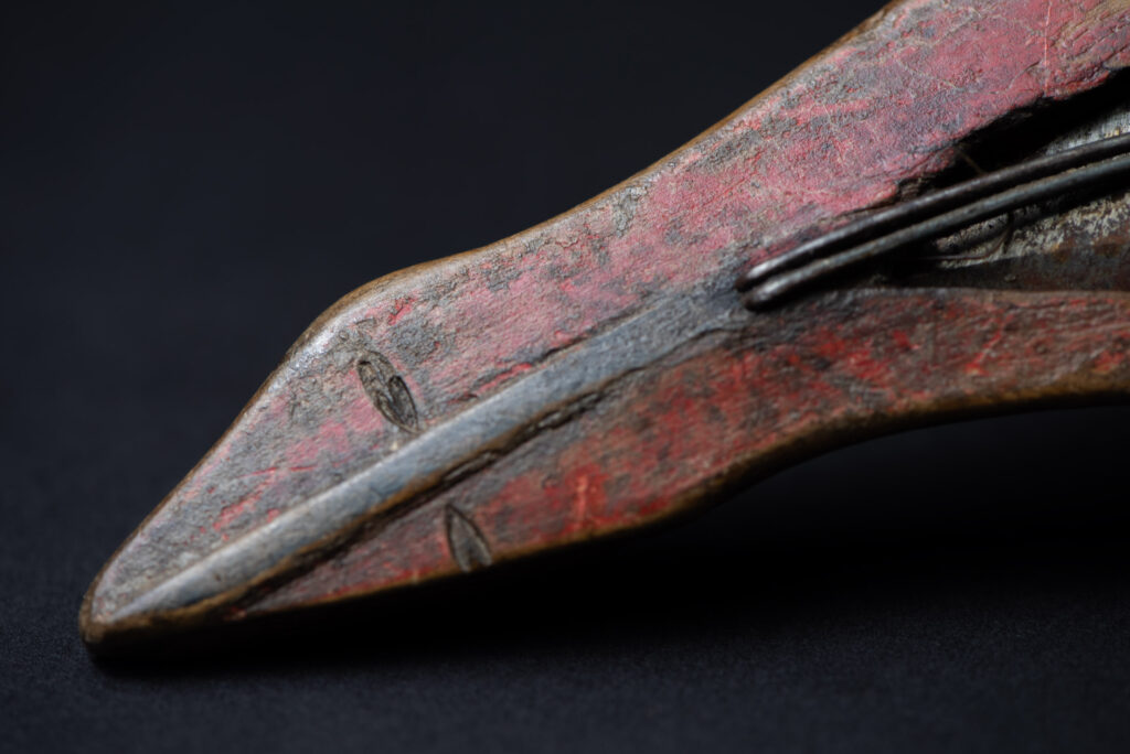 Paiwan tribe hunting knife with a sheath carved with a standing figure and painted in red. The blade and handle are forged as one piece, with the grip wrapped in rattan for protection.