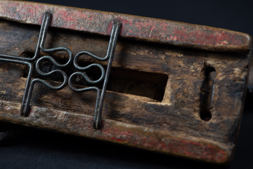 Paiwan tribe hunting knife with a sheath carved with a standing figure and painted in red. The blade and handle are forged as one piece, with the grip wrapped in rattan for protection.