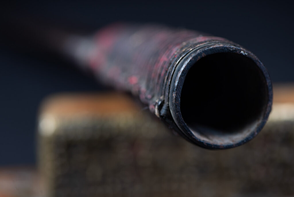 Hunting sword from the Paiwan tribe, with a sheath carved with a scene of a hunter accompanied by his dog shooting at deer. The sides and top of the sheath are covered with brass sheets finely embossed with human head motifs. The sword is made in one piece with the handle, which is wrapped in red-stained rattan.