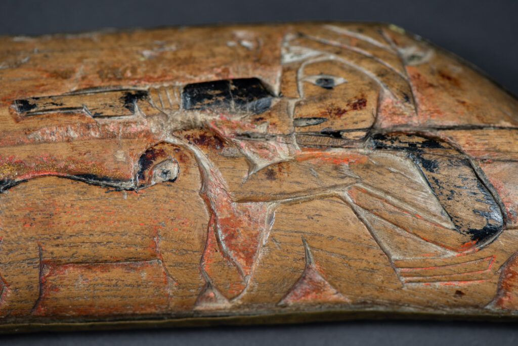 Hunting sword from the Paiwan tribe, with a sheath carved with a scene of a hunter accompanied by his dog shooting at deer. The sides and top of the sheath are covered with brass sheets finely embossed with human head motifs. The sword is made in one piece with the handle, which is wrapped in red-stained rattan.