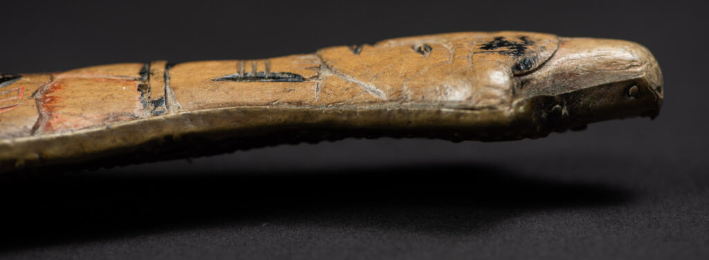 Hunting sword from the Paiwan tribe, with a sheath carved with a scene of a hunter accompanied by his dog shooting at deer. The sides and top of the sheath are covered with brass sheets finely embossed with human head motifs. The sword is made in one piece with the handle, which is wrapped in red-stained rattan.