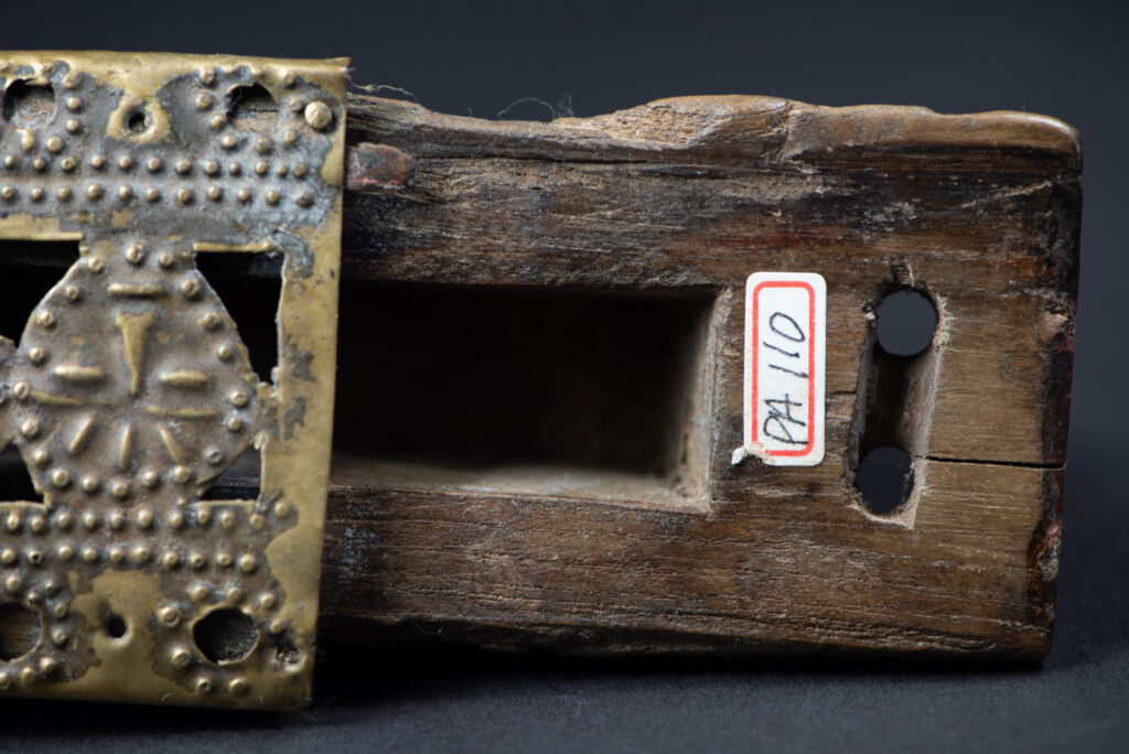Hunting sword from the Paiwan tribe, with a sheath carved with a scene of a hunter accompanied by his dog shooting at deer. The sides and top of the sheath are covered with brass sheets finely embossed with human head motifs. The sword is made in one piece with the handle, which is wrapped in red-stained rattan.