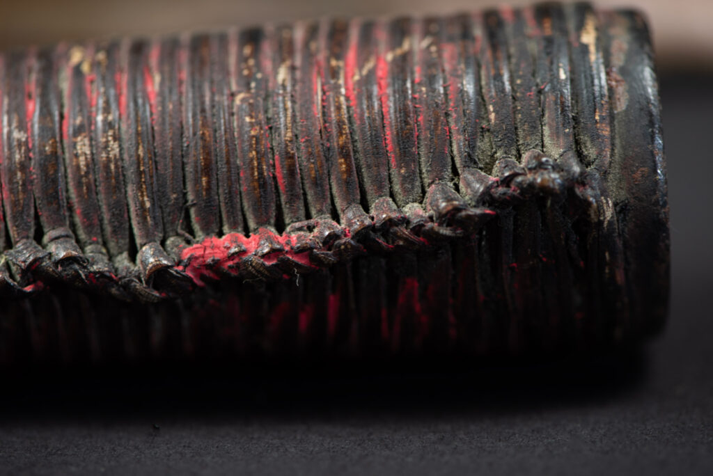 Hunting sword from the Paiwan tribe, with a sheath carved with a scene of a hunter accompanied by his dog shooting at deer. The sides and top of the sheath are covered with brass sheets finely embossed with human head motifs. The sword is made in one piece with the handle, which is wrapped in red-stained rattan.