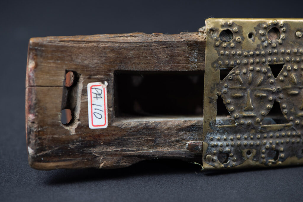 Hunting sword from the Paiwan tribe, with a sheath carved with a scene of a hunter accompanied by his dog shooting at deer. The sides and top of the sheath are covered with brass sheets finely embossed with human head motifs. The sword is made in one piece with the handle, which is wrapped in red-stained rattan.