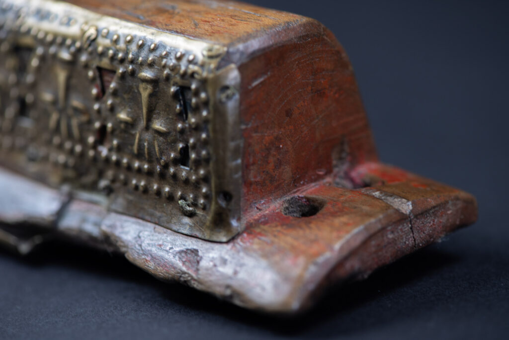 Hunting sword from the Paiwan tribe, with a sheath carved with a scene of a hunter accompanied by his dog shooting at deer. The sides and top of the sheath are covered with brass sheets finely embossed with human head motifs. The sword is made in one piece with the handle, which is wrapped in red-stained rattan.