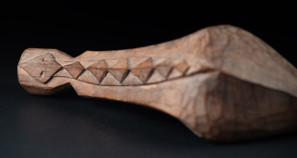 Old wooden spoon from the Paiwan tribe, carved with a one hundred pace snake at the back and one human head and sacred snake at the front.