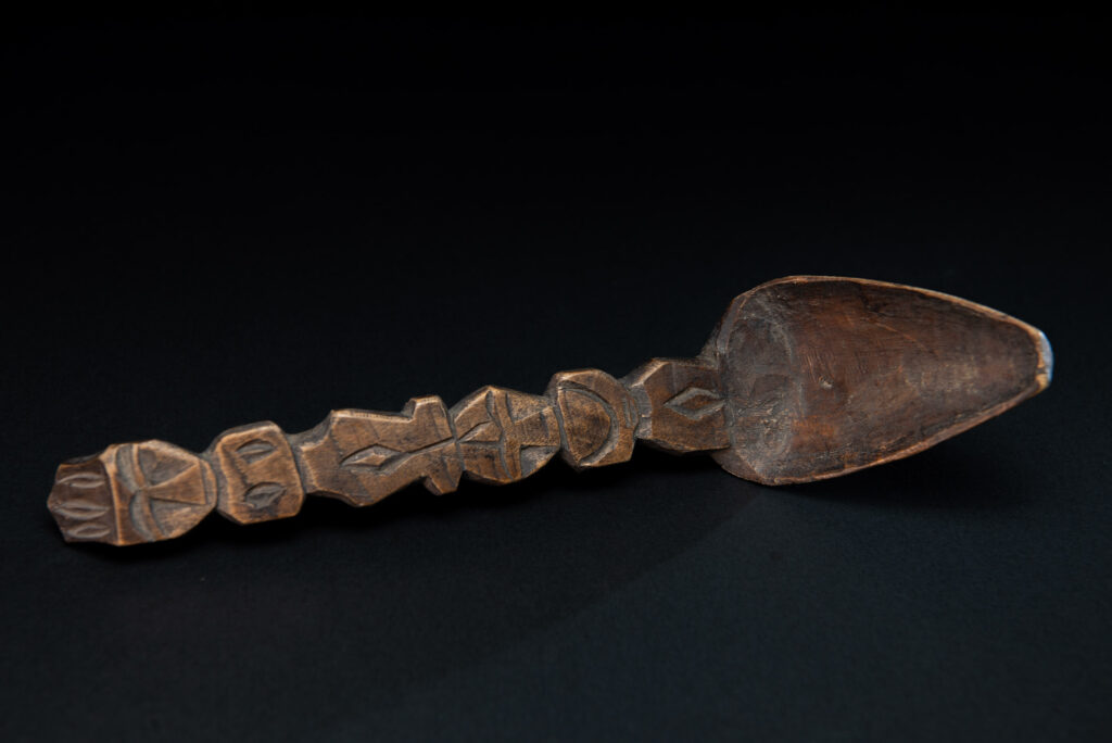 Old spoon from the Paiwan tribe, carved with two full-length standing figures, one above the other.