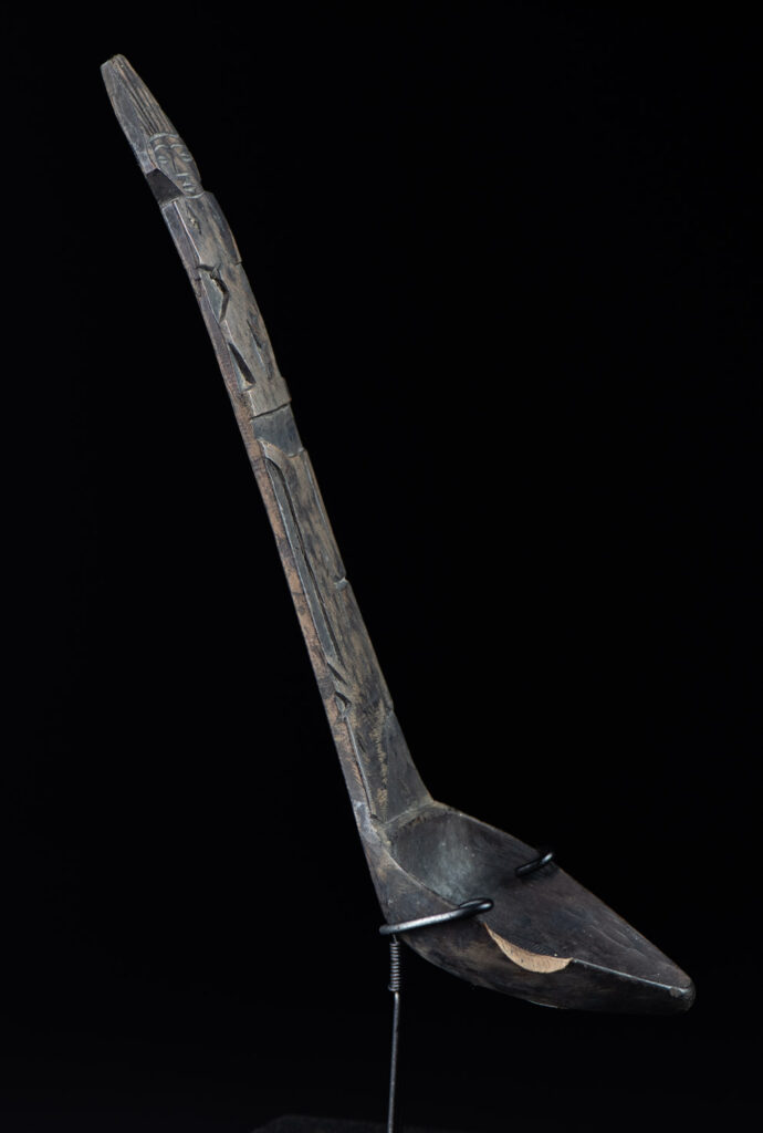 Old wooden spoon from the Paiwan tribe, carved with a standing figure and a deer at its feet.