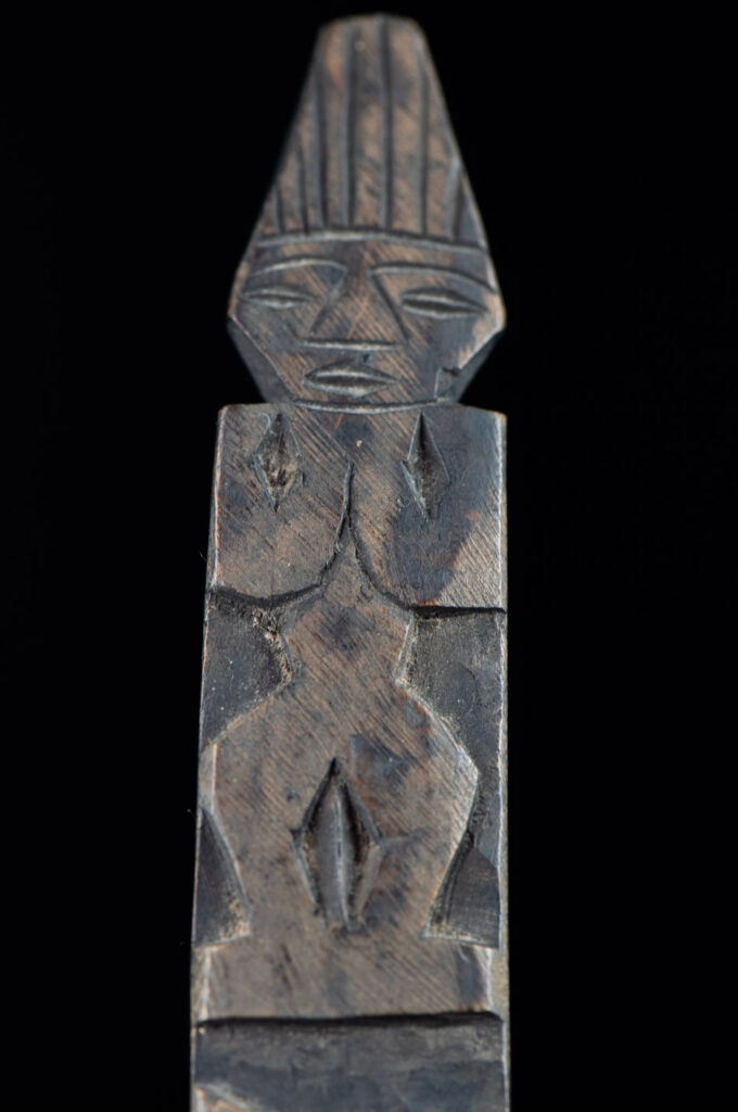 Old wooden spoon from the Paiwan tribe, carved with a standing figure and a deer at its feet.