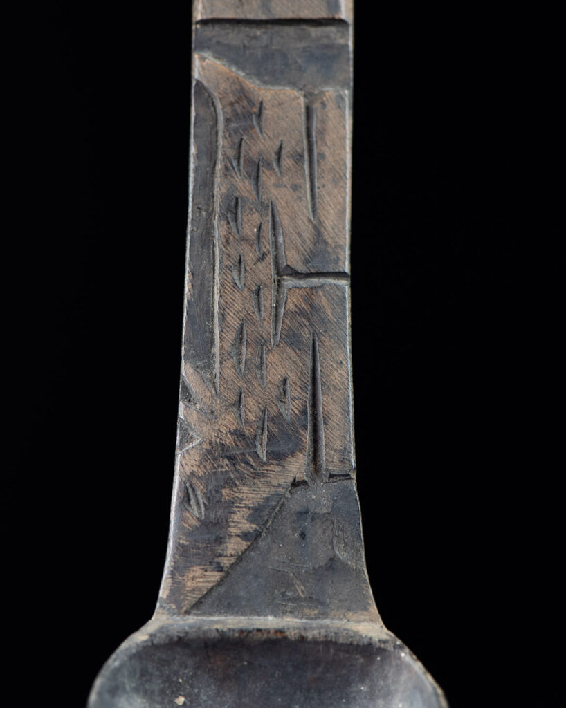 Old wooden spoon from the Paiwan tribe, carved with a standing figure and a deer at its feet.