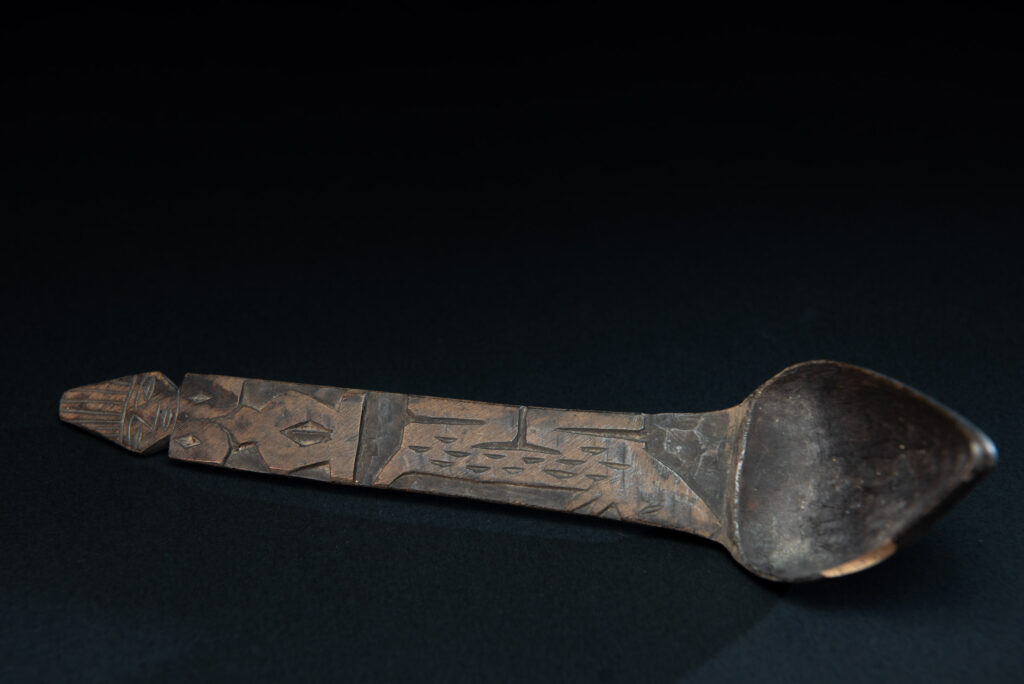 Old wooden spoon from the Paiwan tribe, carved with a standing figure and a deer at its feet.