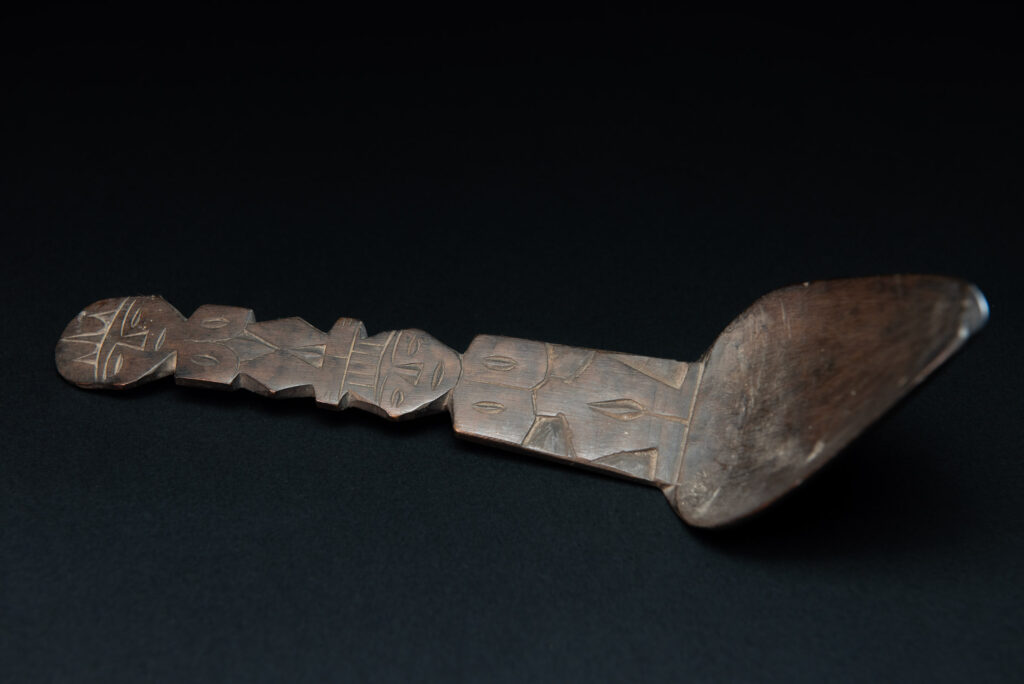 Old wooden spoon from the Paiwan tribe, carved with two full-length standing figures, one above the other.