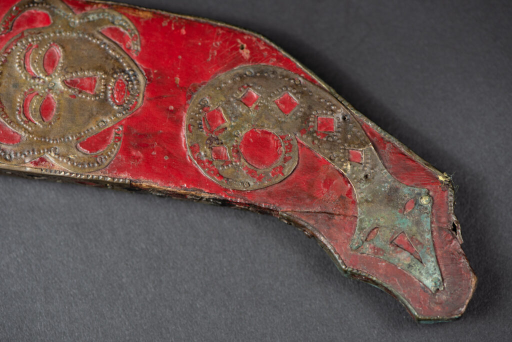 Ancient ceremonial long sword from the Rukai tribe. The back of the sheath is painted red and inlaid with finely engraved snakes in brass sheet. The top is also covered with an engraved brass plate. The very long blade of this Rukai sword features a handle in the Rukai style, decorated with small flower-shaped motifs and aluminum wire. The guard of the sword is made from a Japanese coin.