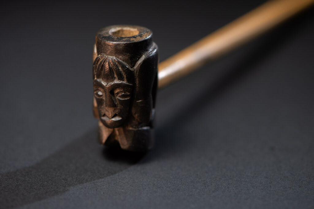 Very fine pipe made of precious wood from the Paiwan tribe, carved with human faces representing a Paiwan warrior and a stylised deer. The bottom is carved in a deer hoof shape.