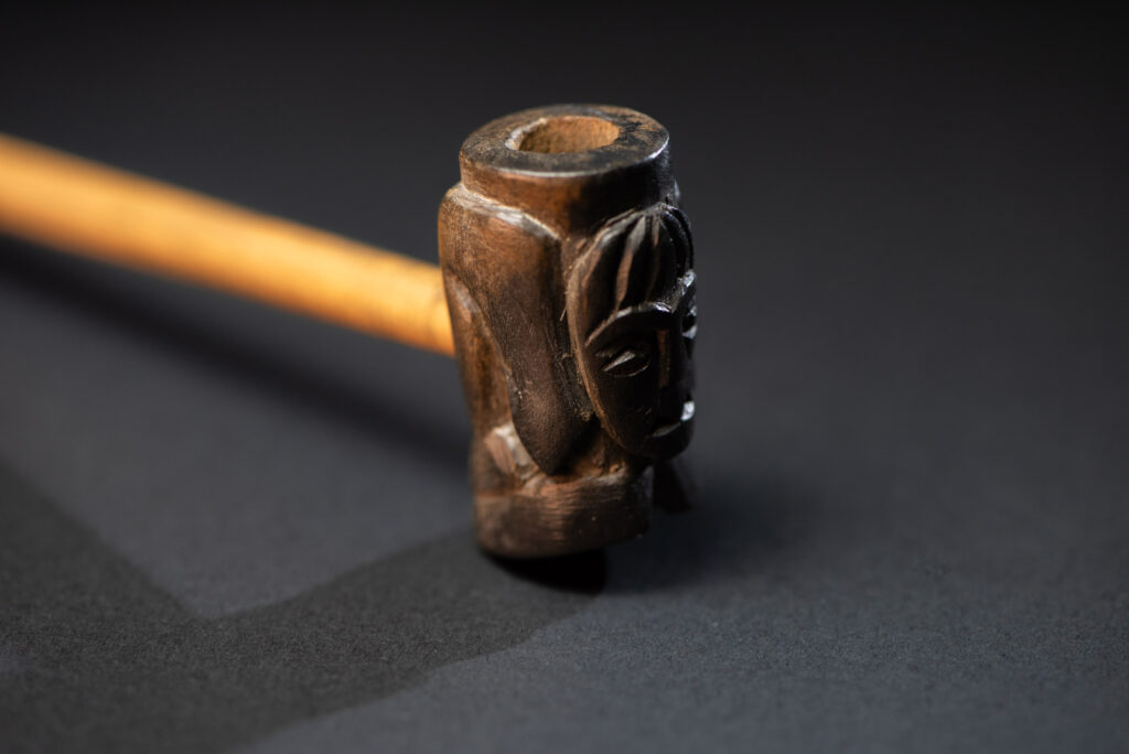 Very fine pipe made of precious wood from the Paiwan tribe, carved with human faces representing a Paiwan warrior and a stylised deer. The bottom is carved in a deer hoof shape.
