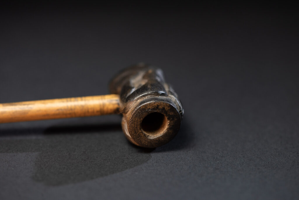 Very fine pipe made of precious wood from the Paiwan tribe, carved with human faces representing a Paiwan warrior and a stylised deer. The bottom is carved in a deer hoof shape.