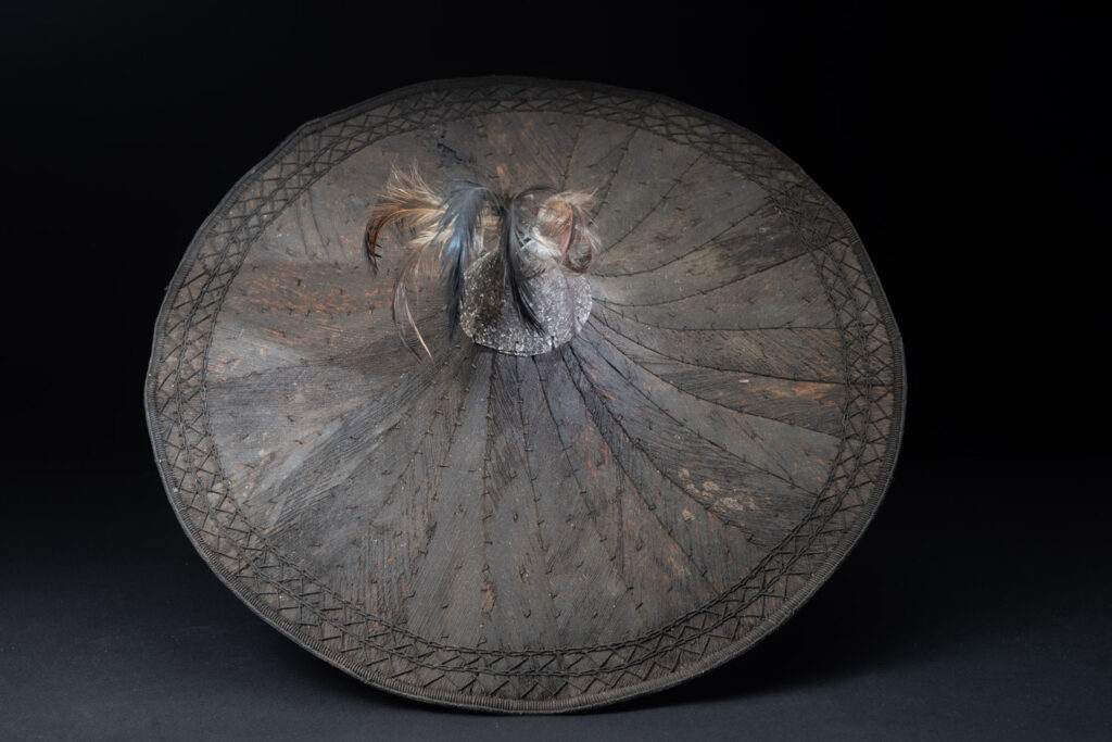 This ancient hat from the Yami- Tao tribes, orchid Island, Taiwan was worn by the female for work in the fields It is named “Varogot”. It is done with coconut palm bark, rotaing, aluminium and feathers for the top decoration..