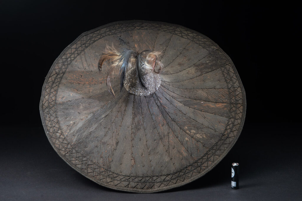 This ancient hat from the Yami- Tao tribes, orchid Island, Taiwan was worn by the female for work in the fields It is named “Varogot”. It is done with coconut palm bark, rotaing, aluminium and feathers for the top decoration..