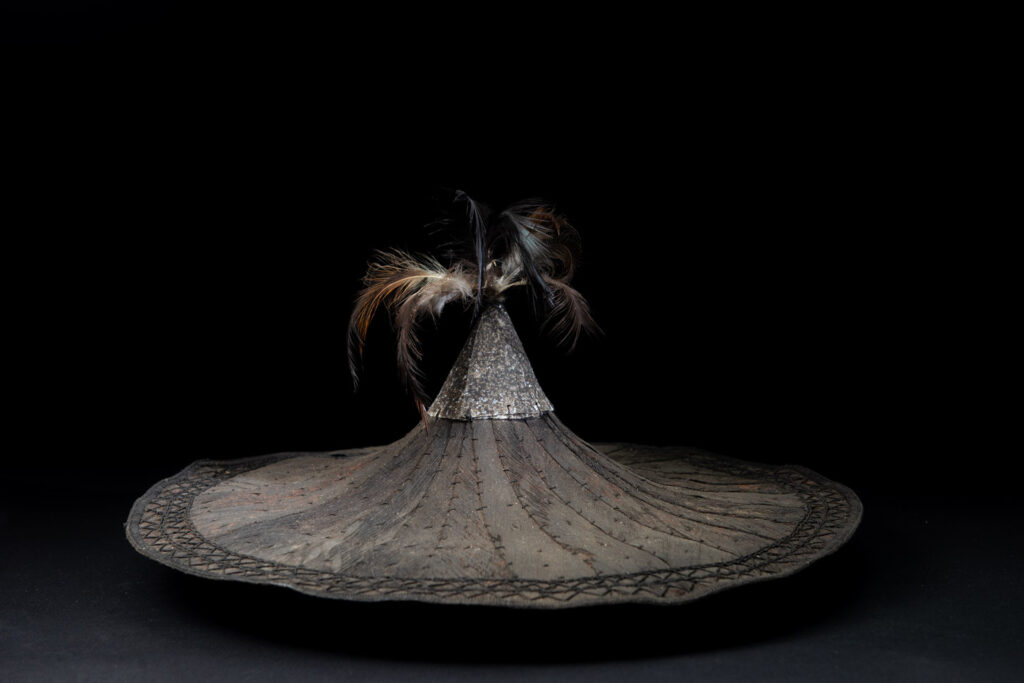 This ancient hat from the Yami- Tao tribes, orchid Island, Taiwan was worn by the female for work in the fields It is named “Varogot”. It is done with coconut palm bark, rotaing, aluminium and feathers for the top decoration..