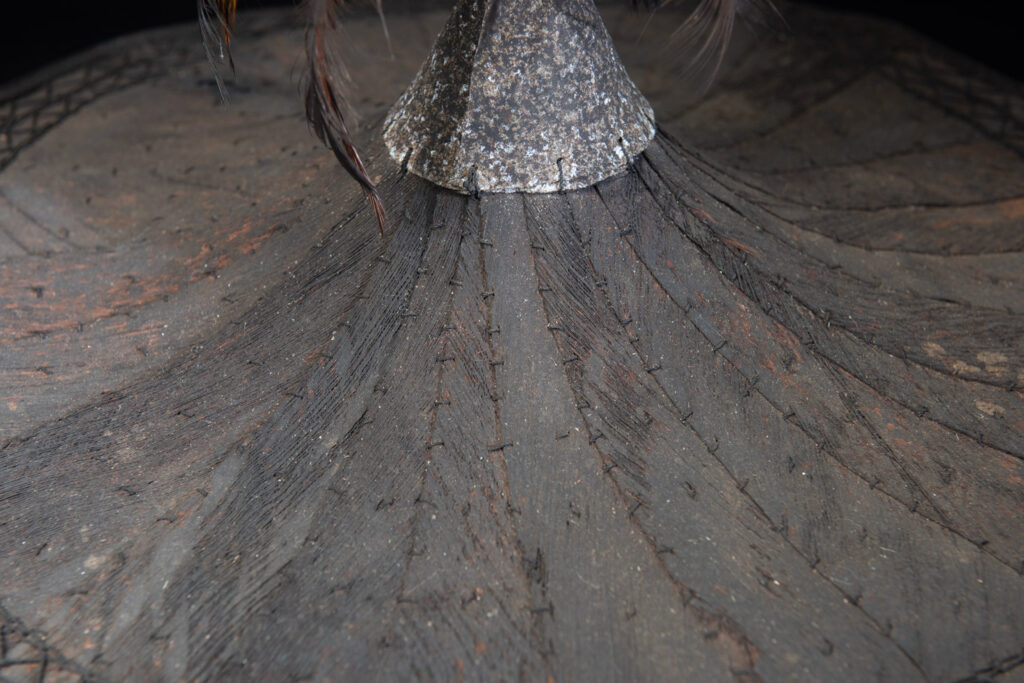 This ancient hat from the Yami- Tao tribes, orchid Island, Taiwan was worn by the female for work in the fields It is named “Varogot”. It is done with coconut palm bark, rotaing, aluminium and feathers for the top decoration..
