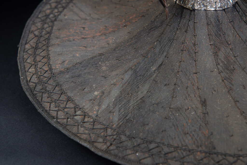 This ancient hat from the Yami- Tao tribes, orchid Island, Taiwan was worn by the female for work in the fields It is named “Varogot”. It is done with coconut palm bark, rotaing, aluminium and feathers for the top decoration..